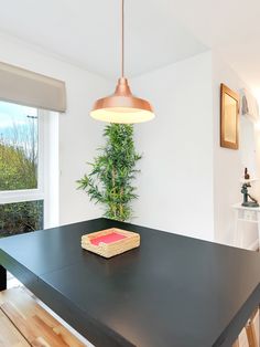 a table with a basket on it in front of a window and a potted plant