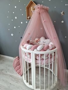 a white crib with pink bedding and stars on the wall next to it