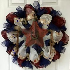 a patriotic mesh wreath hanging on the front door with stars and stripes in red, white, and blue