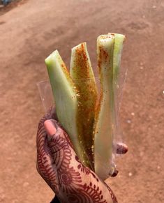 someone holding up some type of plant with dirt on the ground in the backgroud