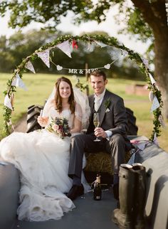 a bride and groom are sitting on the back of an old tractor with their champagne