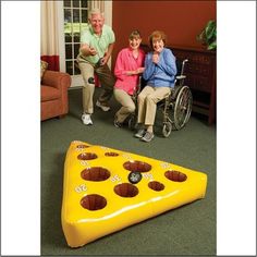 an older man and woman sitting in front of a giant pizza shaped like a game