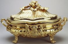 an ornate gold covered box with flowers on top