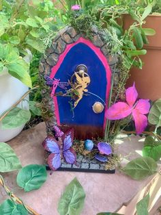 a blue fairy door surrounded by plants and flowers