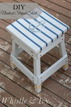 a small white stool sitting on top of a wooden floor next to a blue and white striped seat