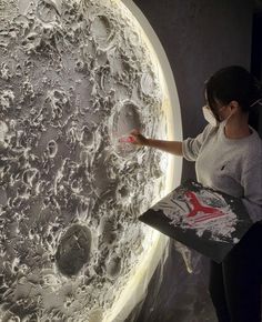 a woman is standing in front of a large circular object that looks like the moon