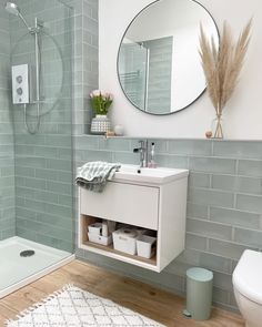 a white sink sitting under a bathroom mirror next to a walk in shower and toilet