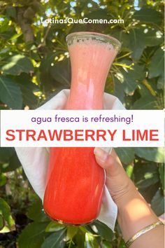 a person holding up a pink drink in front of green leaves with the words aqua fresca is refreshing strawberry lime