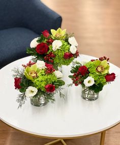 three vases filled with flowers sitting on top of a white table next to a blue chair