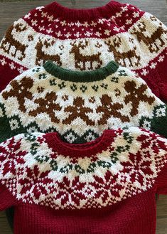 three knitted sweaters sitting on top of a wooden table