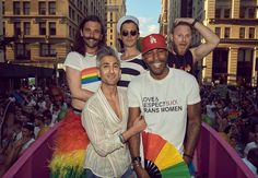 a group of men standing next to each other on top of a rainbow colored float