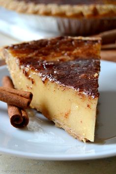 a slice of cheesecake on a plate with cinnamon sticks