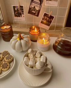 a table topped with cookies and candles on top of a white counter next to pictures