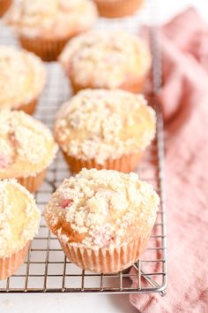 several muffins cooling on a wire rack with pink towels in the back ground