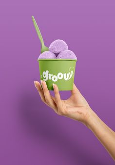 a hand holding up a green cup with two scoops of ice cream