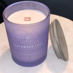 a purple candle sitting on top of a table next to a metal container filled with liquid