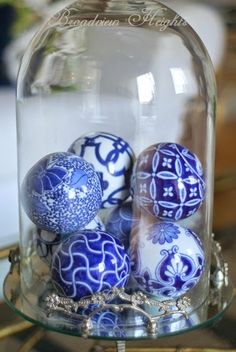 some blue and white balls under a glass clochel on a table top with gold trim