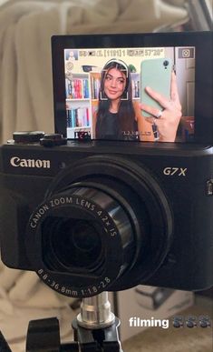 a digital camera is sitting on top of a tripod with the image of a woman's hand