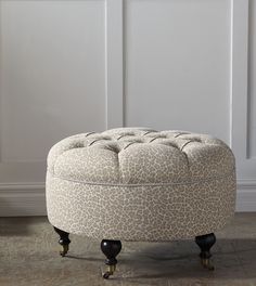 an upholstered ottoman sits on wheels in front of a white wall