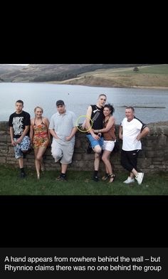 a group of people standing next to each other in front of a body of water