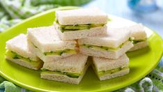 several sandwiches stacked on top of each other on a green plate next to a blue and white towel