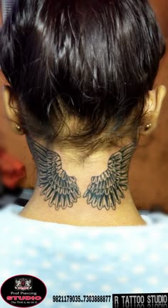 the back of a woman's neck with an angel wing tattoo on her neck