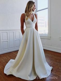 a woman in a white wedding dress is standing by a window with her back to the camera