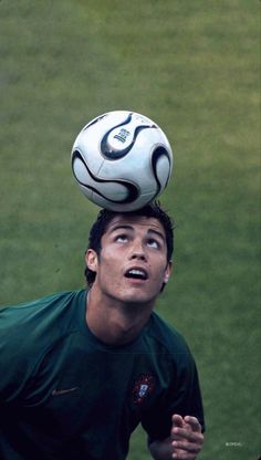 a young man is balancing a soccer ball on his head in the air over his head