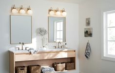 a bathroom with two sinks, mirrors and baskets on the floor in front of it