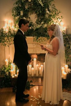 a bride and groom standing in front of candles