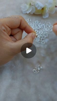 two hands are working on beading with white flowers in the background and text that reads creative zinaz