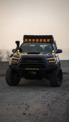 the front end of a black truck with yellow lights on it's headlamps