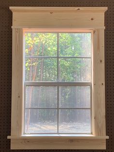 an open window in a wood paneled wall next to a bench and tree line