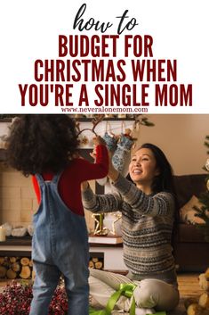 a woman and child playing with christmas decorations in front of the fireplace text reads how to budget for christmas when you're a single mom