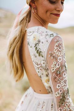 the back of a woman's dress with flowers and leaves on it, in an open field