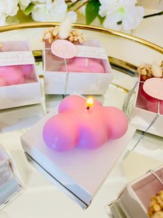 there are four small boxes with pink candles in them on the table next to each other