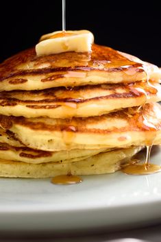 a stack of pancakes on a plate with syrup being drizzled over them