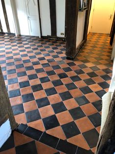 an empty room with black and red tiles on the floor in front of a door