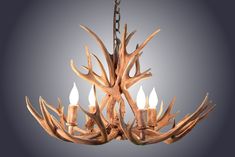 a chandelier made out of antler branches with three candles in the center