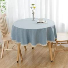 a table with two chairs and a blue tablecloth on it in front of a window