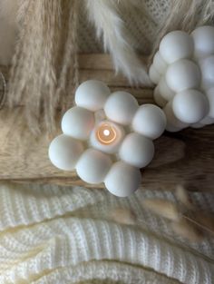 a candle is surrounded by white balls and feathers