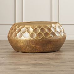 a gold coffee table sitting on top of a hard wood floor next to a white wall