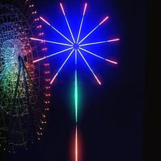 fireworks are lit up in the night sky above an amusement park ferris wheel and roller coaster