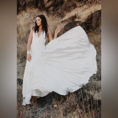 a woman in a white dress is posing for a photo with her long flowing fabric