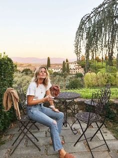 a woman sitting at an outdoor table with a baseball glove in her hand and looking up into the sky