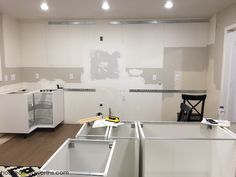 an unfinished kitchen with white cabinets and wood flooring in the process of remodeling