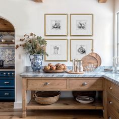 a kitchen with blue and white cabinets and pictures on the wall above the countertop