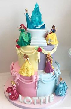 a multi - tiered cake with princess figures on it