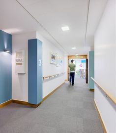 a person walking down a hallway with blue and white walls