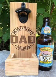 a bottle opener and wooden box sitting on top of a rock next to a beer